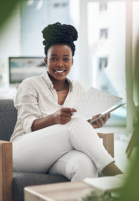 Buy stock photo Shot of a businesswoman using her digital tablet while reading paperwork