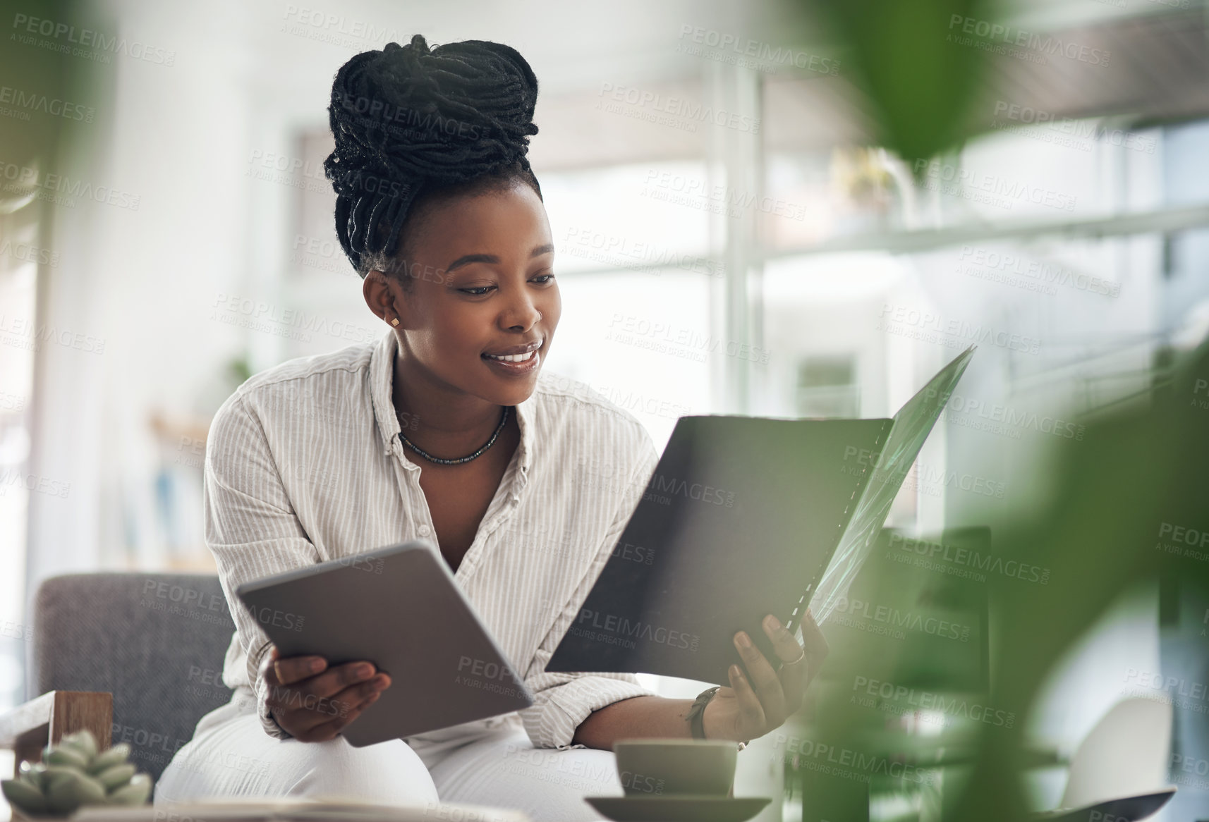 Buy stock photo Shot of a businesswoman using her digital tablet while reading paperwork