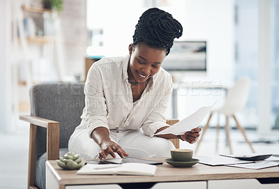 Buy stock photo Shot of a businesswoman using her digital tablet while reading paperwork