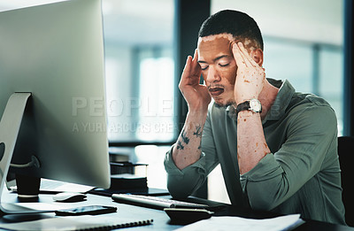 Buy stock photo Shot of a young businessman struggling with a headache while using a computer in an office at work