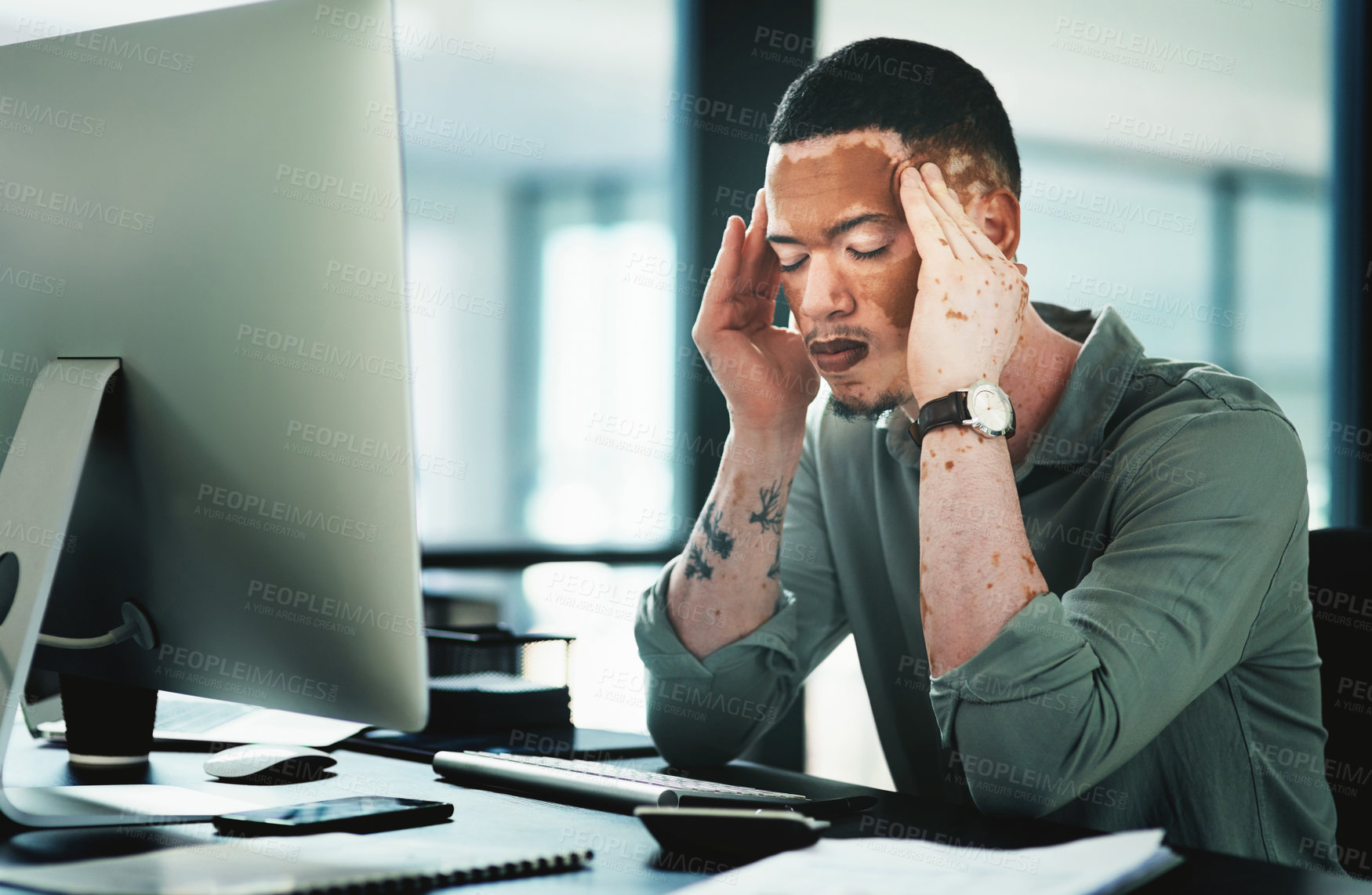 Buy stock photo Shot of a young businessman struggling with a headache while using a computer in an office at work