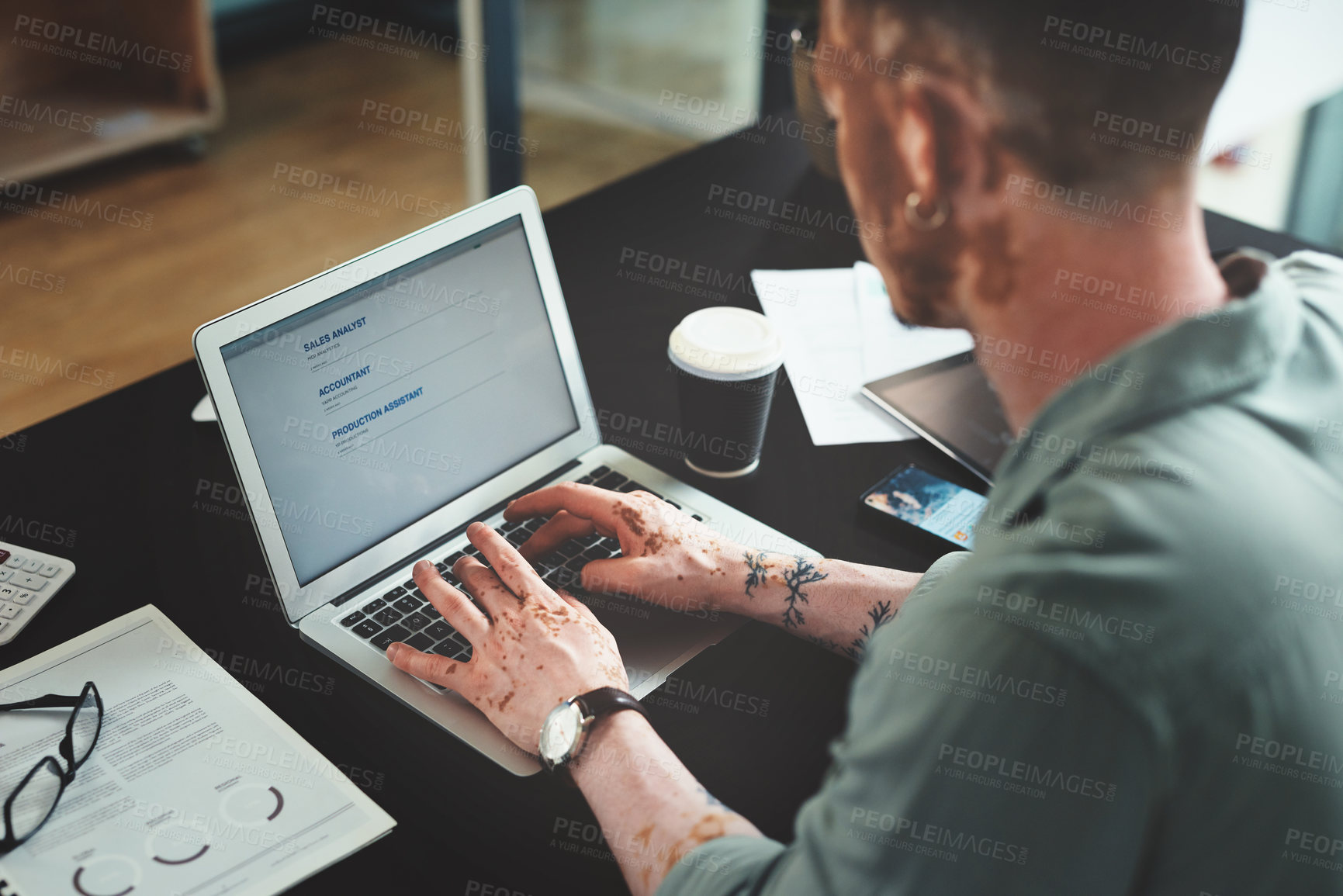 Buy stock photo Shot of a young businessman using a laptop in an office at work