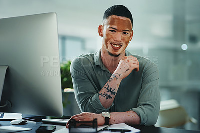 Buy stock photo Shot of a young businessman sitting at a desk in an office at work