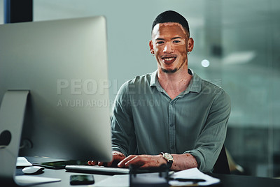 Buy stock photo Shot of a young businessman using a computer in an office at work