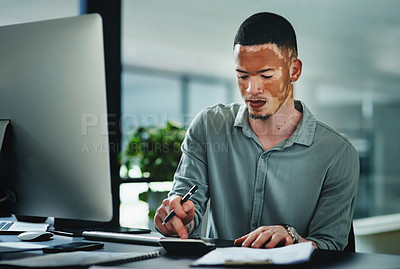 Buy stock photo Shot of a young businessman using a calculator while doing paperwork in an office at work