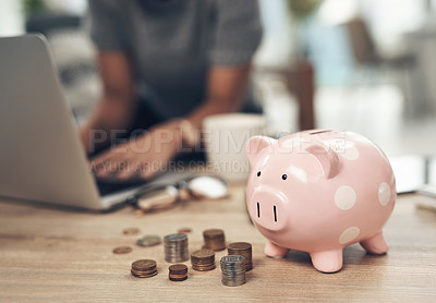 Buy stock photo Closeup shot of coins and a piggybank on a table with an unrecognisable businesswoman working in the background