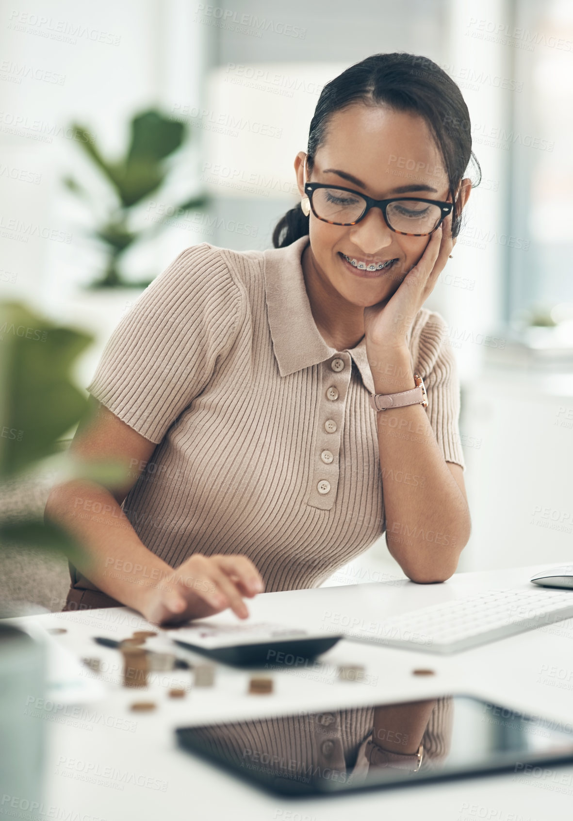 Buy stock photo Shot of a young businesswoman calculating finances in an office
