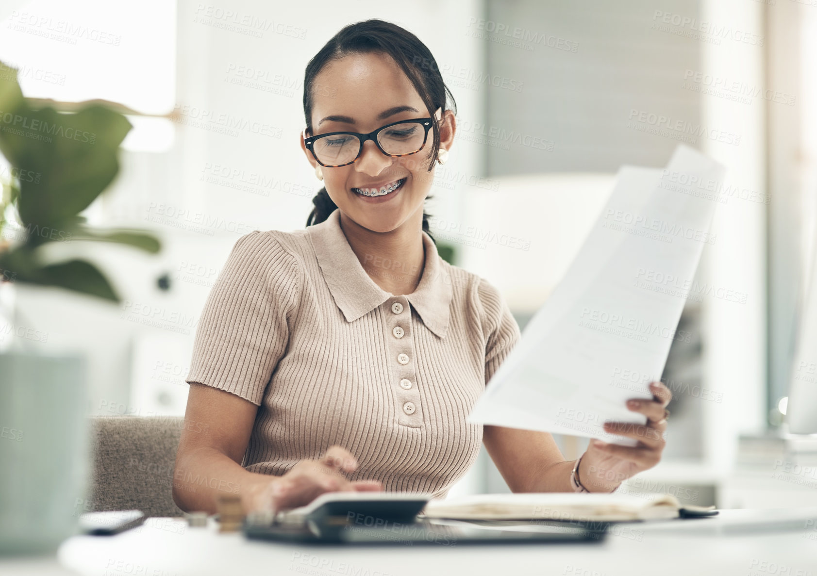 Buy stock photo Shot of a young businesswoman calculating finances in an office