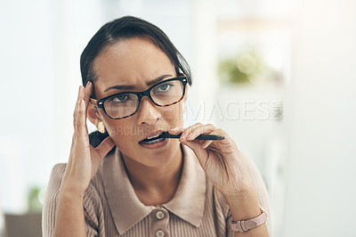 Buy stock photo Shot of a young businesswoman biting a pen while looking thoughtful in an office