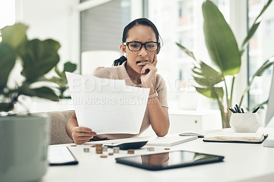 Buy stock photo Shot of a young businesswoman looking stressed out while calculating finances in an office