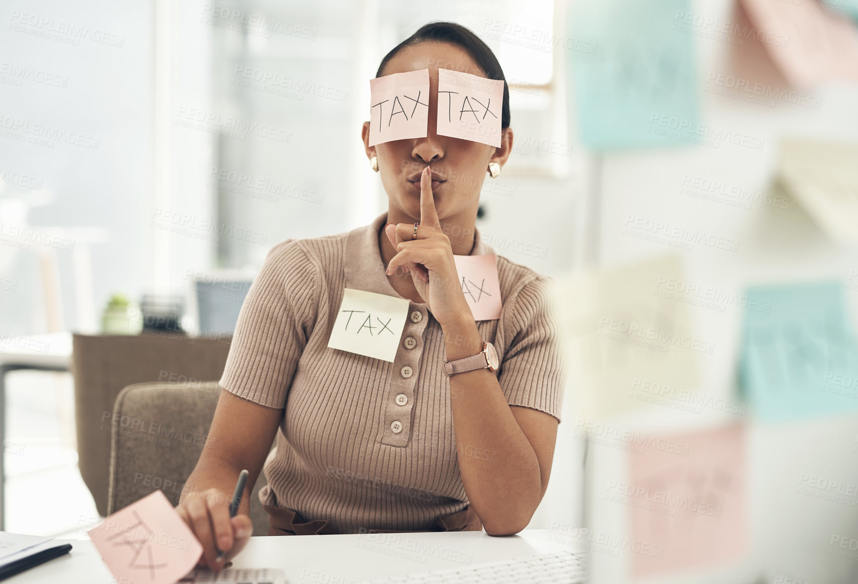 Buy stock photo Shot of a young businesswoman covered in sticky notes and holding her fingers on her lips while working on taxes in an office