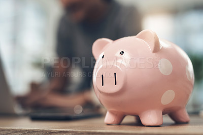 Buy stock photo Closeup shot of a piggybank on a table with an unrecognisable businesswoman working in the background