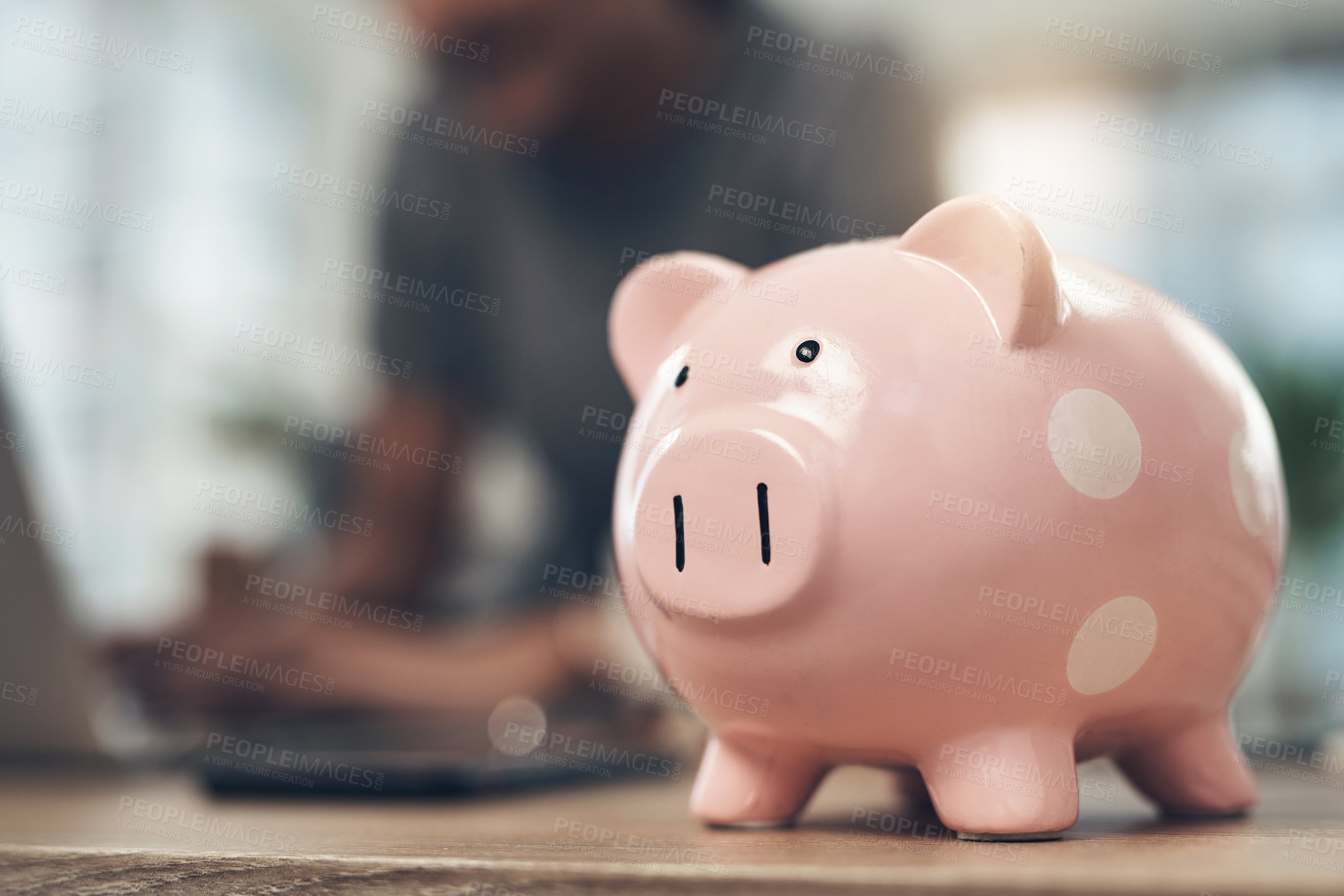 Buy stock photo Closeup shot of a piggybank on a table with an unrecognisable businesswoman working in the background