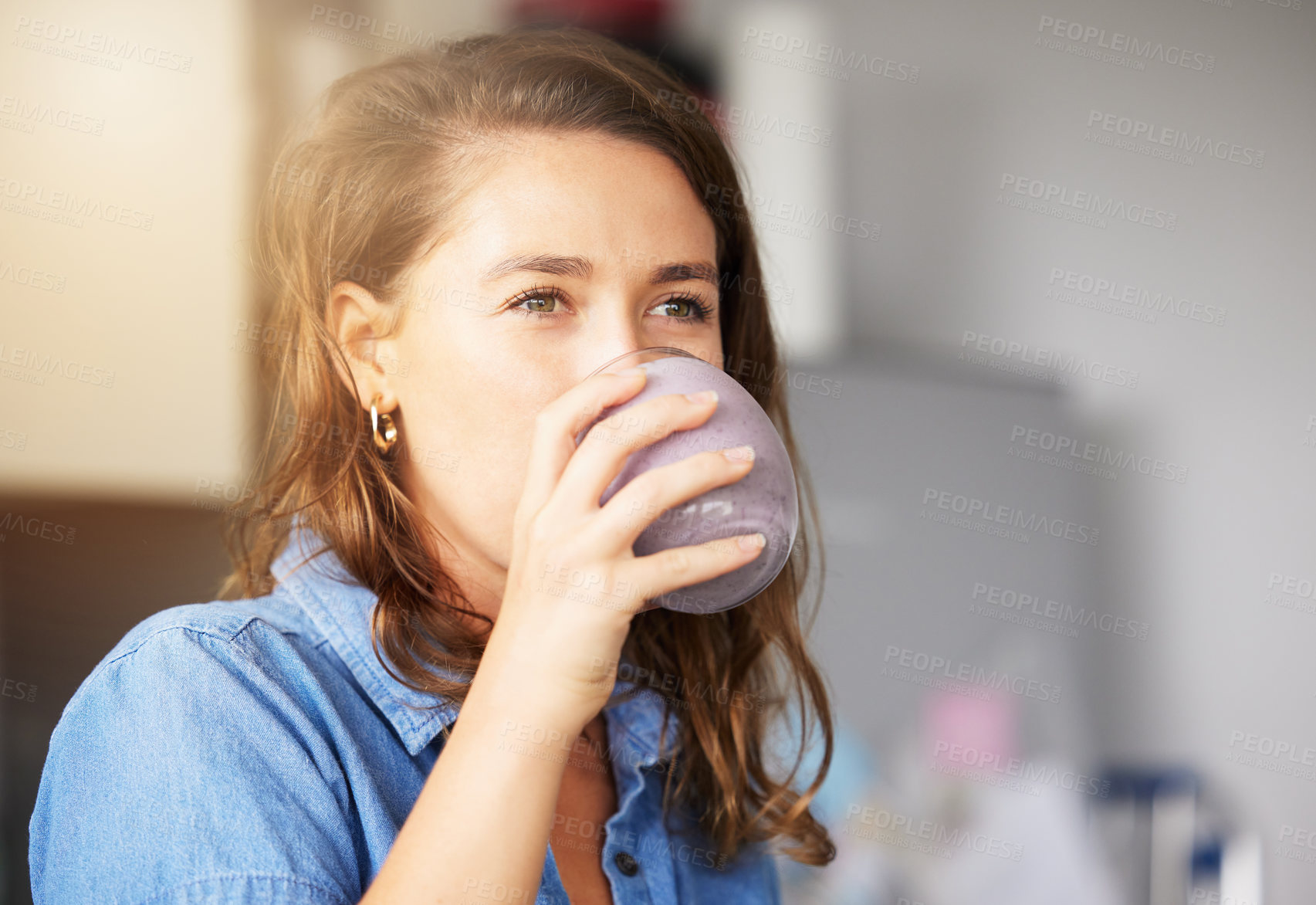 Buy stock photo Shot of a young female drinking a smoothy at home