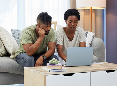 Buy stock photo Shot of a young couple using a laptop while sitting on the couch at home