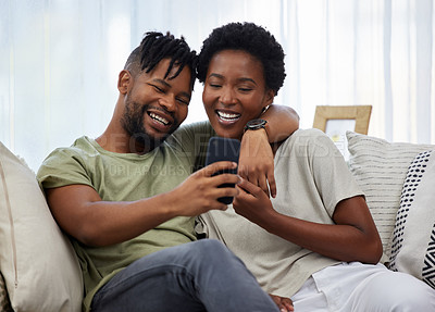 Buy stock photo Shot of a young couple taking a selfie while sitting on the couch at home