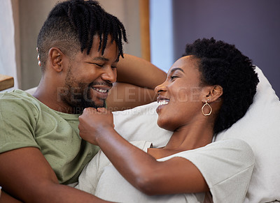 Buy stock photo Shot of a young woman embracing her partner while sitting on a couch at home