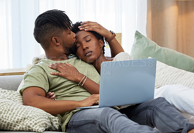 Buy stock photo Shot of a young man kissing his partner on the forehead while using a laptop at home