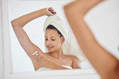 Buy stock photo Full length shot of an attractive young woman standing alone in her bathroom and shaving her underarms after her shower