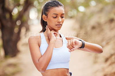 Buy stock photo Shot of a young woman taking her pulse during a jog
