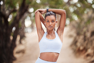 Buy stock photo Woman, portrait and stretching and earphone in nature, runner and body wellness or health in forest. Sports, exercise and listening or music for vitality workout, serious face and training warm up 