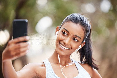 Buy stock photo Shot of a young woman using her smartphone to take selfies on her daily jog