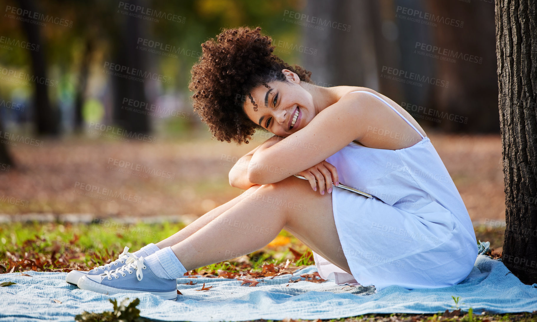 Buy stock photo Full length portrait of an attractive young woman smiling happily while sitting in the park