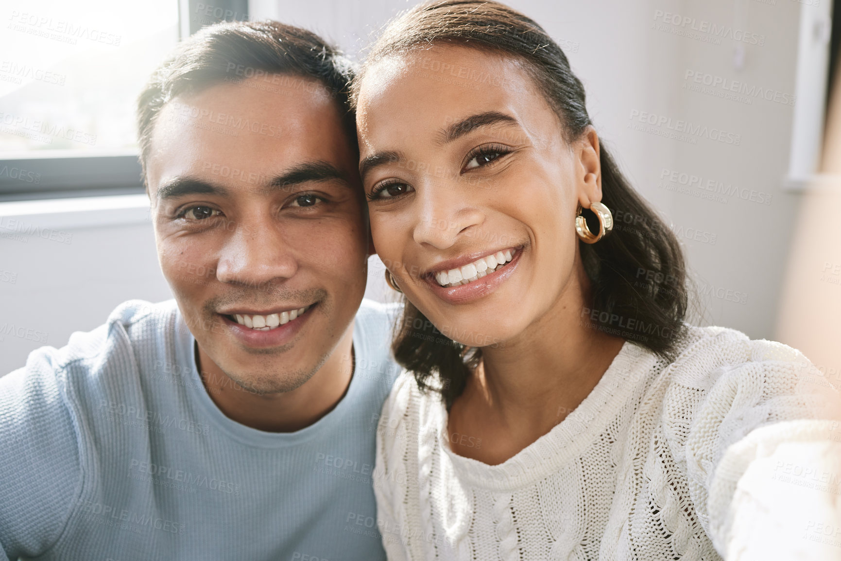 Buy stock photo Shot of a young couple sitting together and taking a selfie in their new home