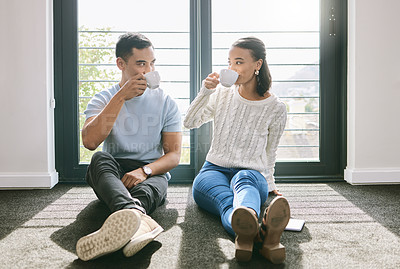 Buy stock photo Full length of a young couple sitting together in their new home and enjoying a cup of tea