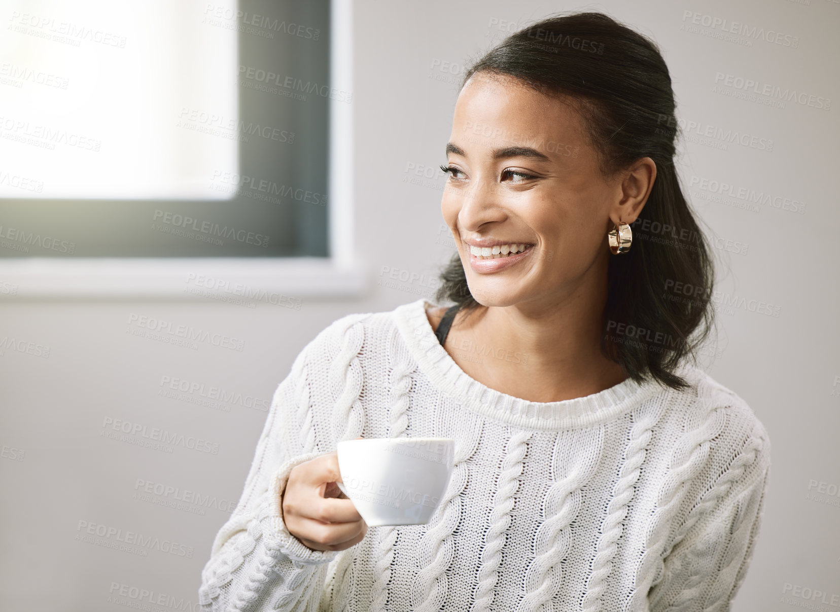 Buy stock photo Shot of an attractive young woman sitting alone in her new home and enjoying a cup of tea