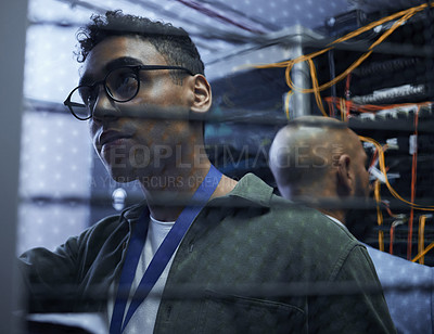 Buy stock photo Cropped shot of two male IT support agents working together in a dark network server room