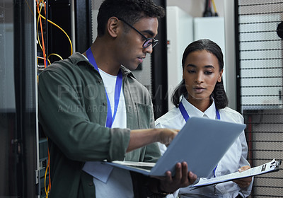 Buy stock photo Cropped shot of two young IT support agents working together in a dark network server room