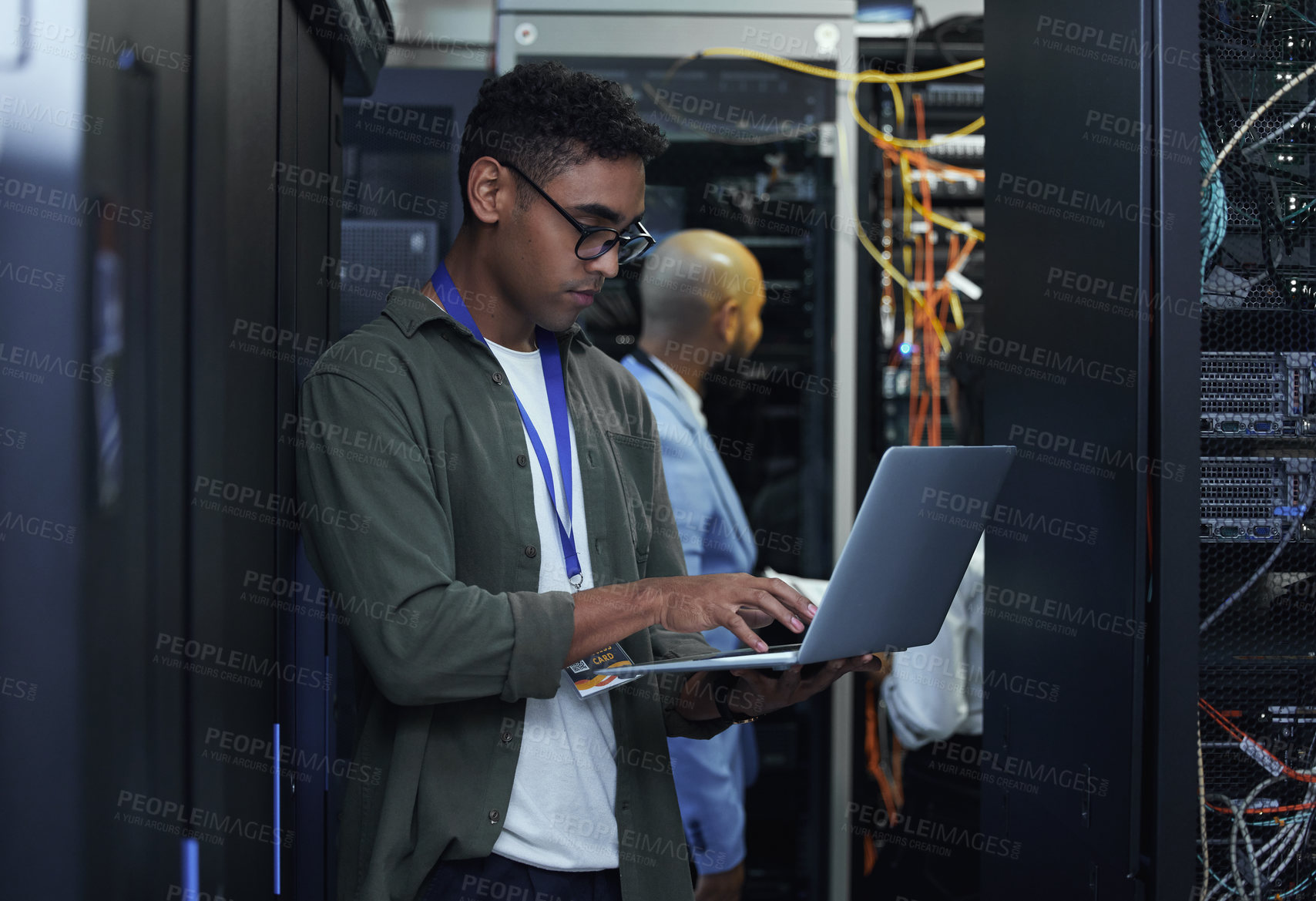 Buy stock photo Cropped shot of two male IT support agents working together in a dark network server room