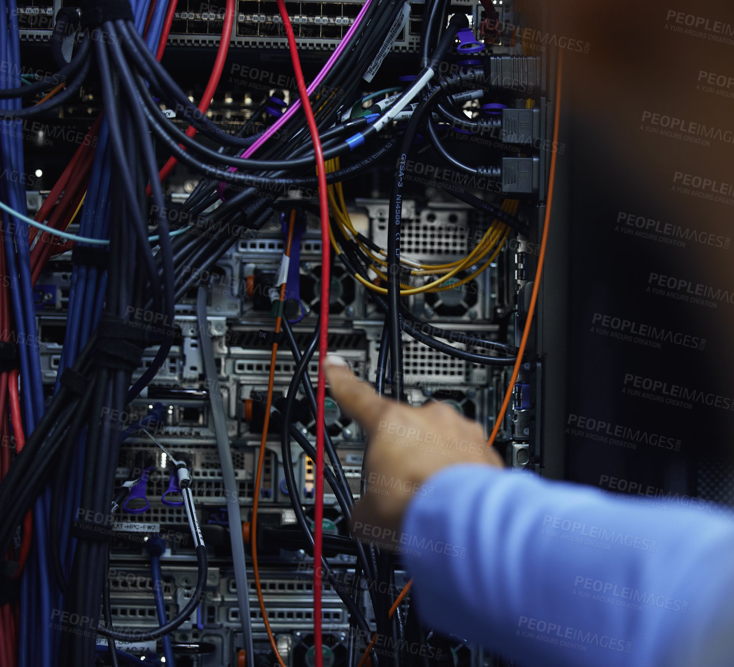 Buy stock photo Cropped shot of an unrecognizable male IT support agent working in a dark network server room