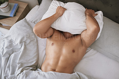 Buy stock photo High angle shot of an unrecognizable young man lying in bed with his pillow over his head