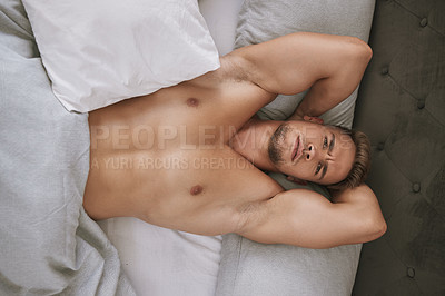 Buy stock photo High angle portrait of a handsome and muscular young man lying in his bed at home