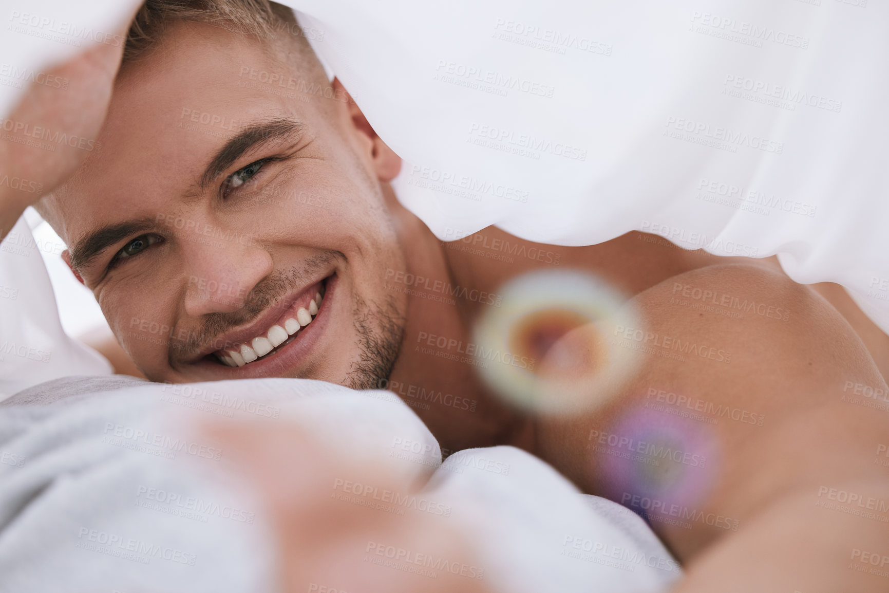 Buy stock photo Cropped portrait of a handsome and muscular young man lying in his bed at home