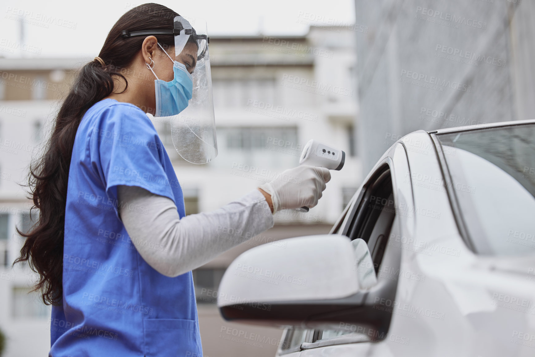 Buy stock photo Shot of a young healthcare worker taking a patient's temperature at a drive through vaccination site
