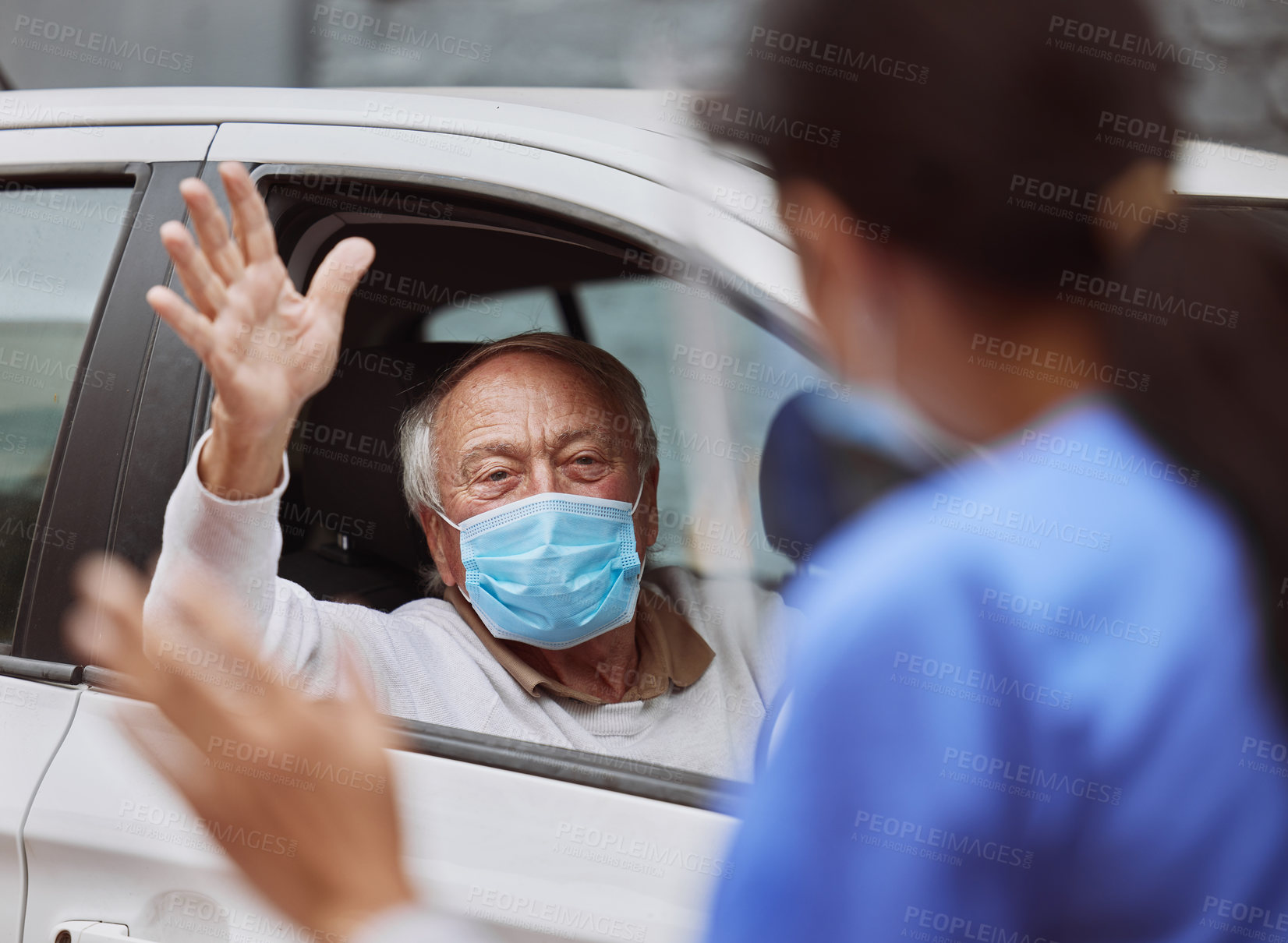 Buy stock photo Shot of a healthcare worker waving at a patient at a drive through vaccination site
