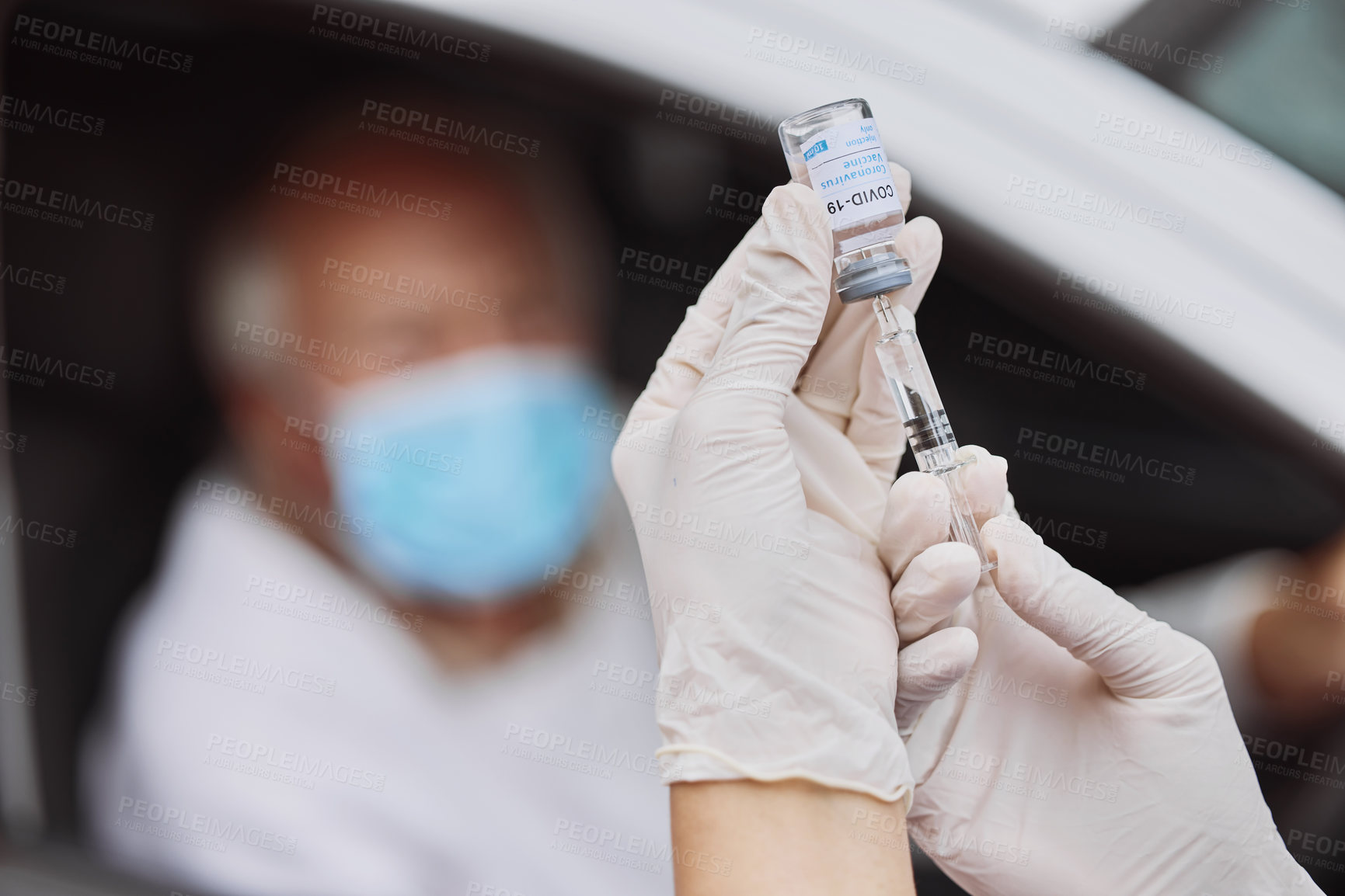 Buy stock photo Shot of an unrecognizable healthcare worker extracting liquid from a vial with a syringe at a drive through vaccination site