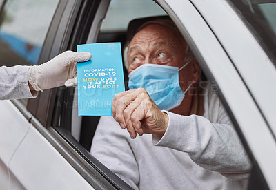 Buy stock photo Shot of a senior man taking a pamphlet from a healthcare worker at a drive through vaccination site