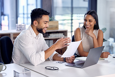 Buy stock photo Shot of two work colleagues reading over some documents together