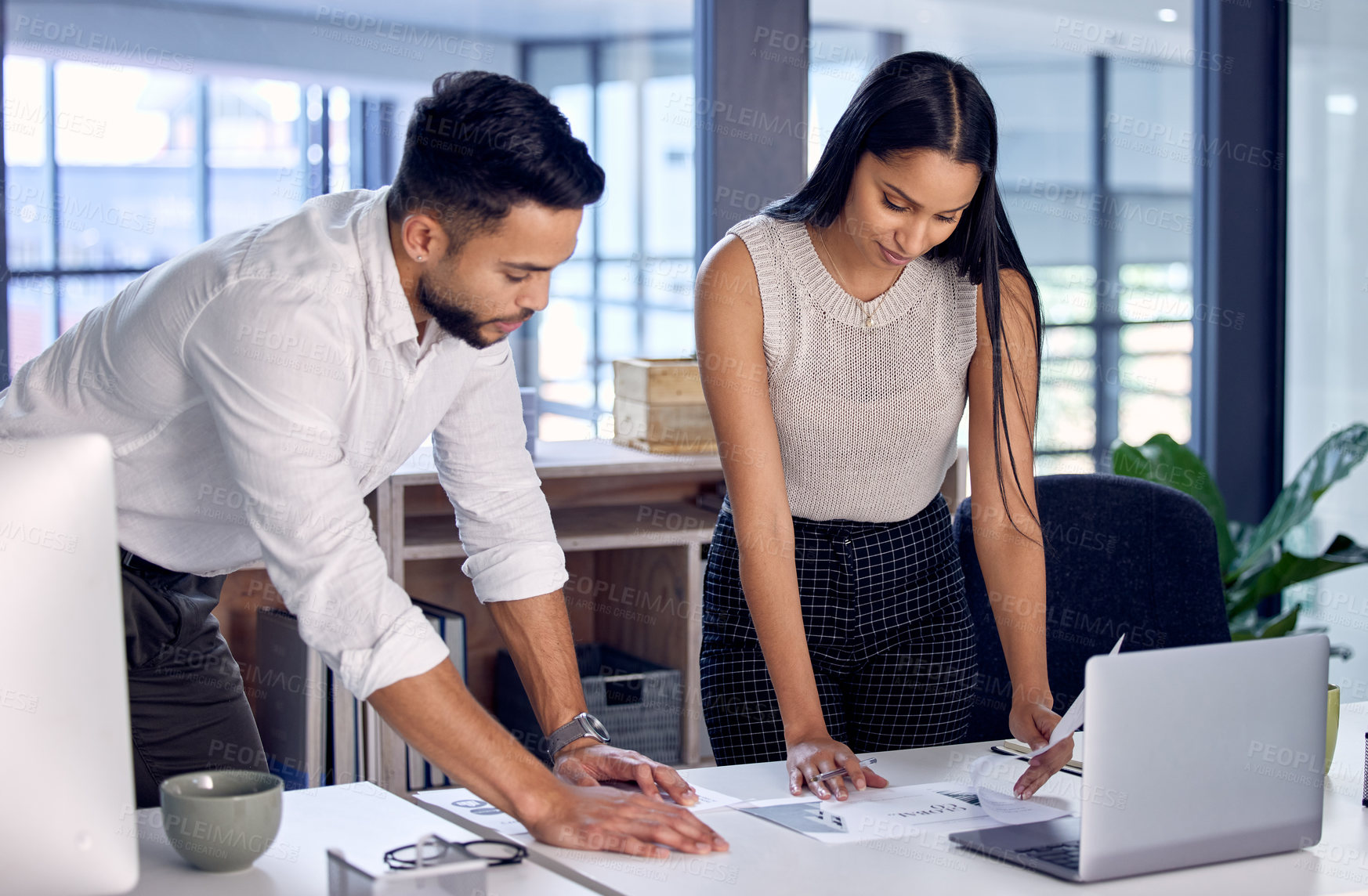 Buy stock photo Shot of two work colleagues reading over some documents together