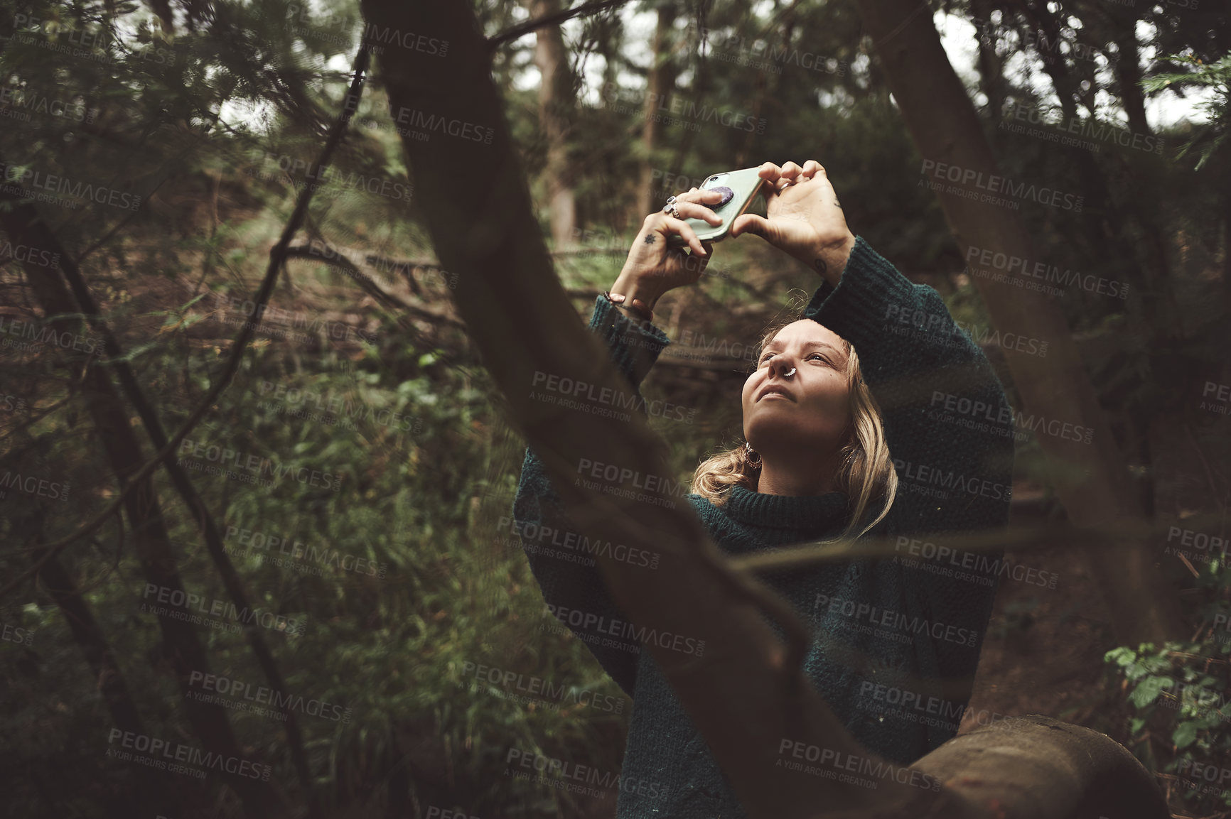 Buy stock photo Shot of a woman using her cellphone to take pictures while out exploring nature