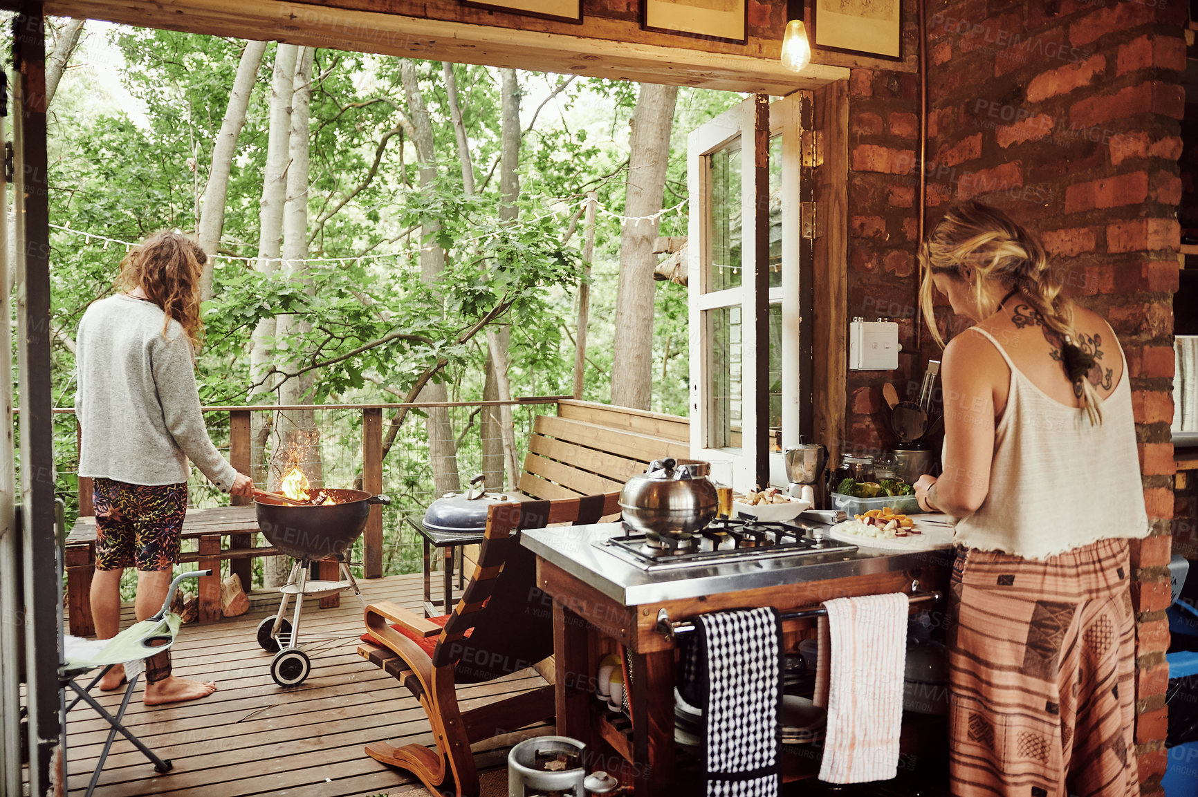 Buy stock photo Shot of a young couple preparing dinner while on vacation in a cabin