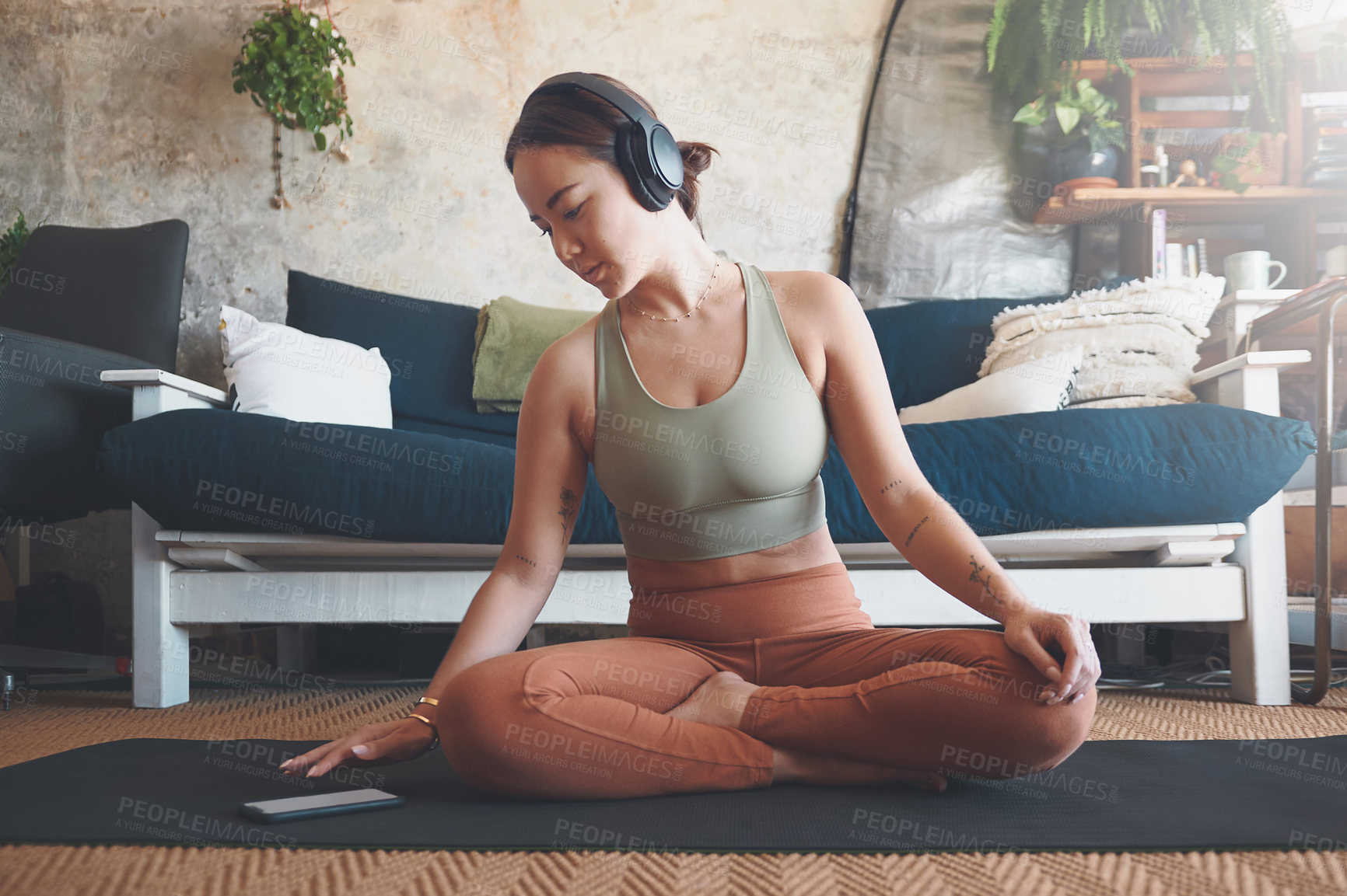 Buy stock photo Shot of a young woman using a cellphone while exercising at home