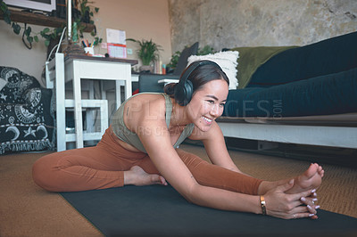 Buy stock photo Shot of a young woman stretching her legs while exercising at home