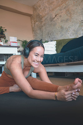 Buy stock photo Shot of a young woman stretching her legs while exercising at home