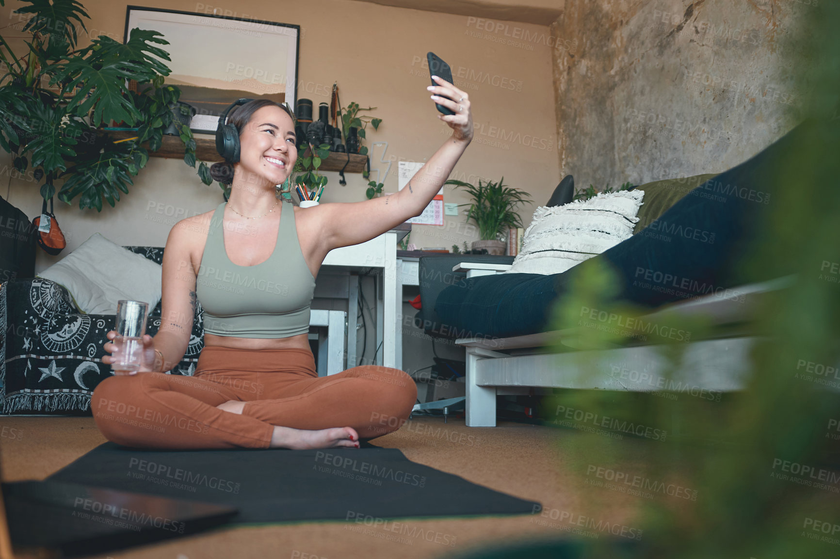 Buy stock photo Shot of a young woman using a cellphone while exercising at home