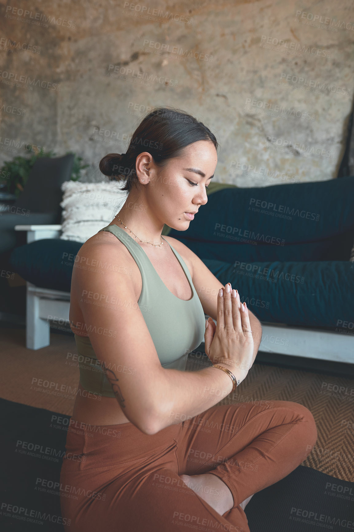 Buy stock photo Shot of a young woman meditating while practising yoga at home
